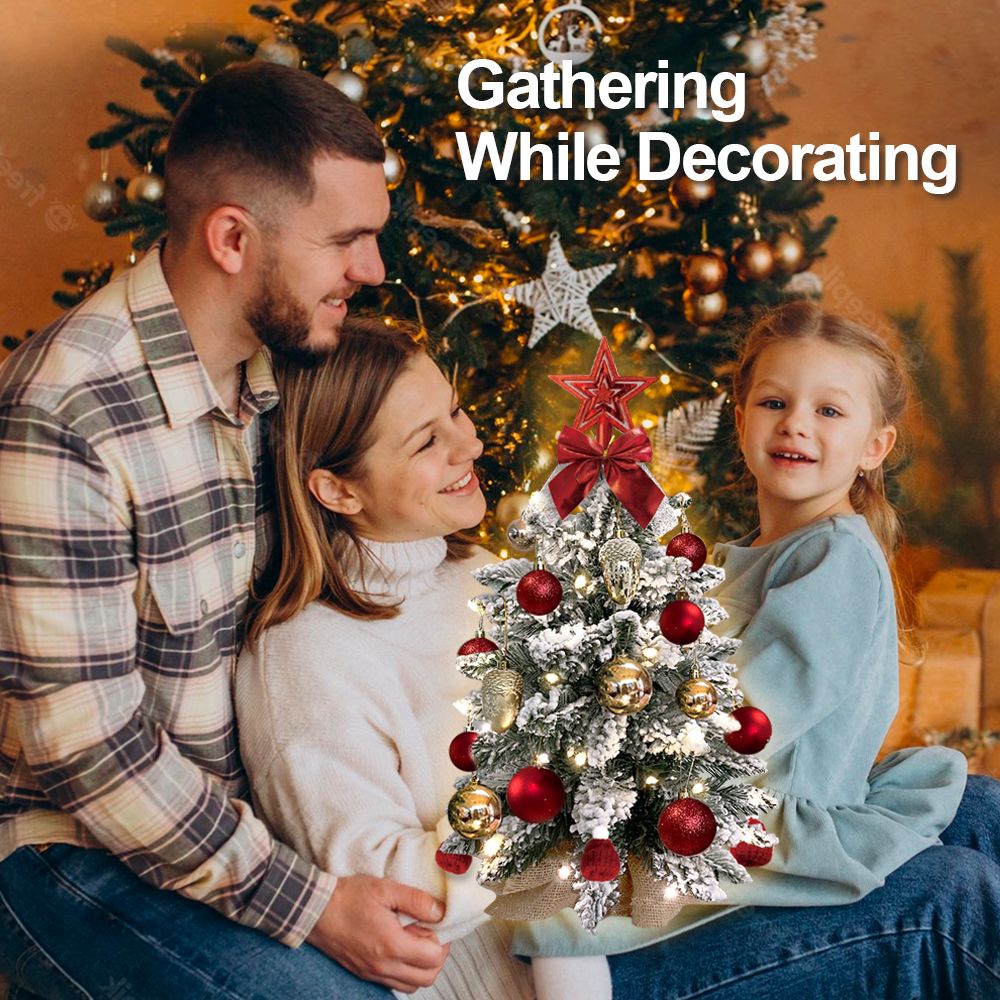 Family smiling and decorating a 22 inch artificial Christmas tree silver with red and gold ornaments