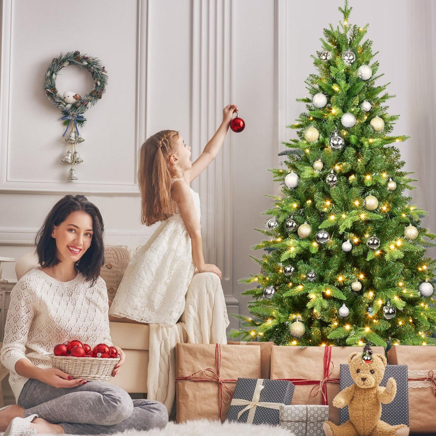 Family decorating a 6ft pre-lit Christmas tree with ornaments and gifts for the holiday season