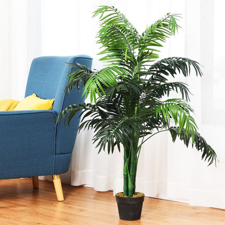 Artificial areca palm tree in a black pot next to a blue armchair for home decor