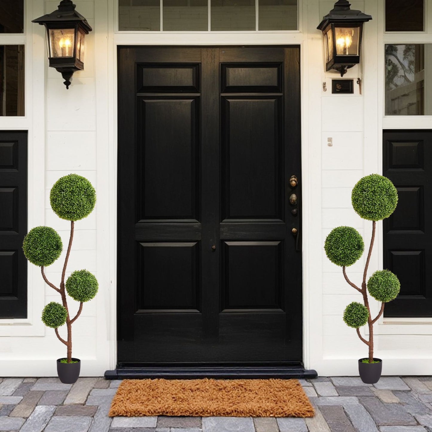 Two stylish artificial boxwood topiary plants in decorative pots at a black front door