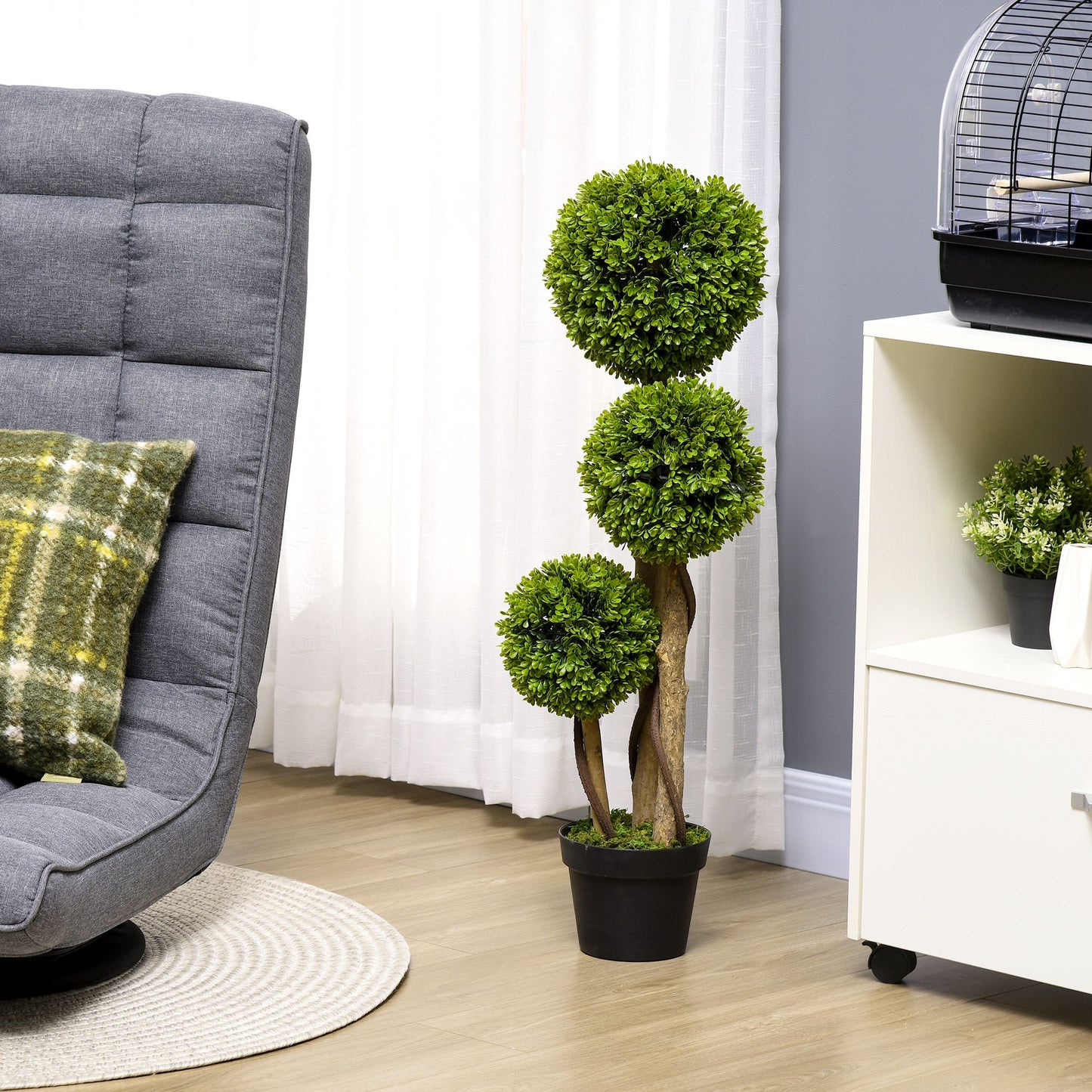 Decorative artificial boxwood topiary balls in a stylish living room setting with grey chair and pillows