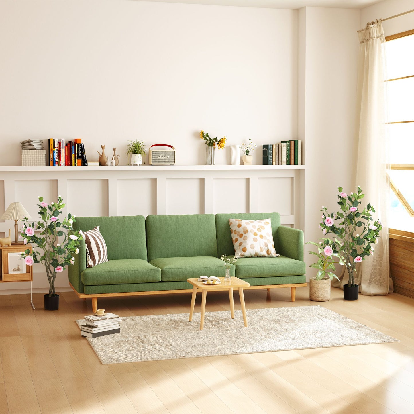 Living room with green sofa and artificial camellia flowers in pots on either side near windows