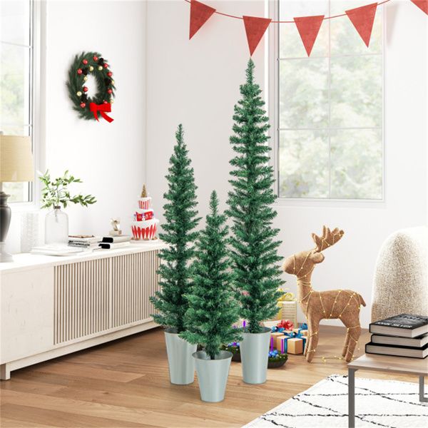 Three tall artificial Christmas tree set in stylish pots for festive indoor decoration