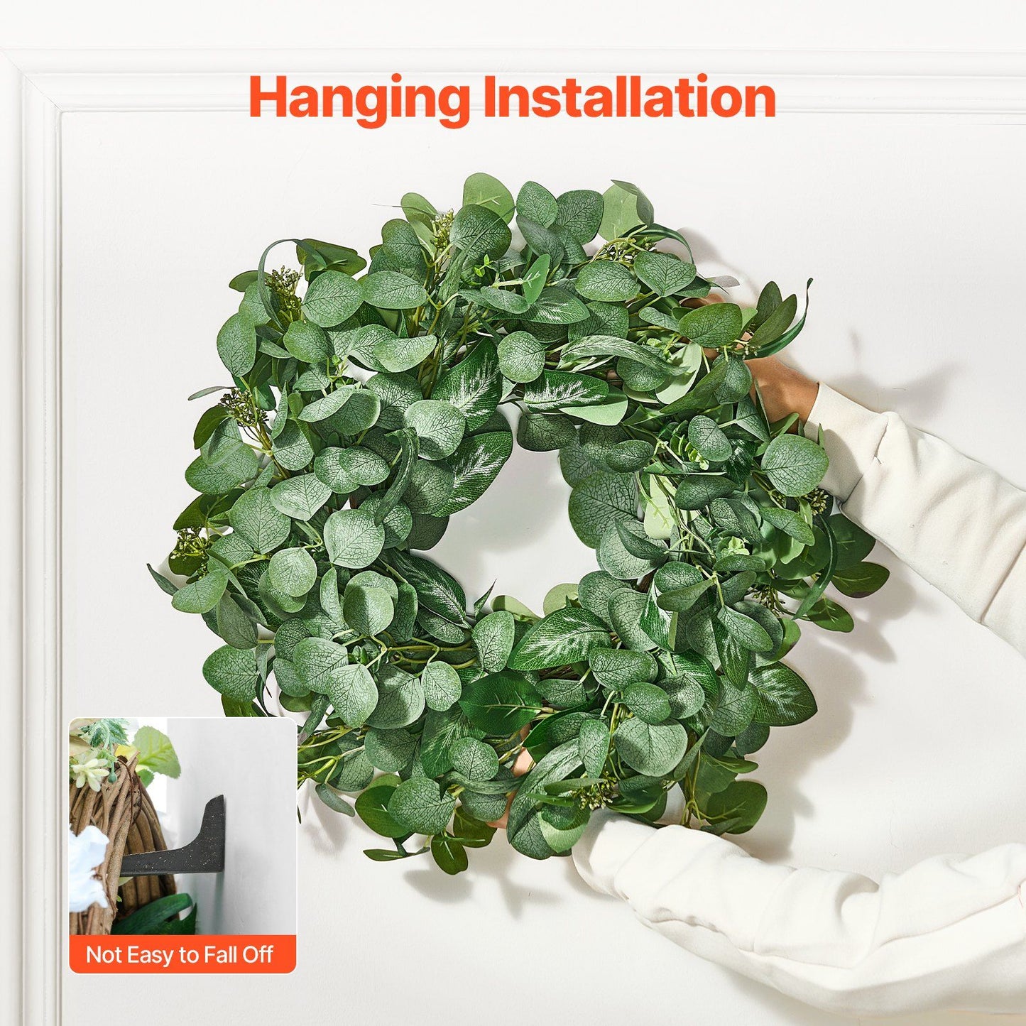 Hands holding an artificial eucalyptus wreath hanging on a white wall with easy installation