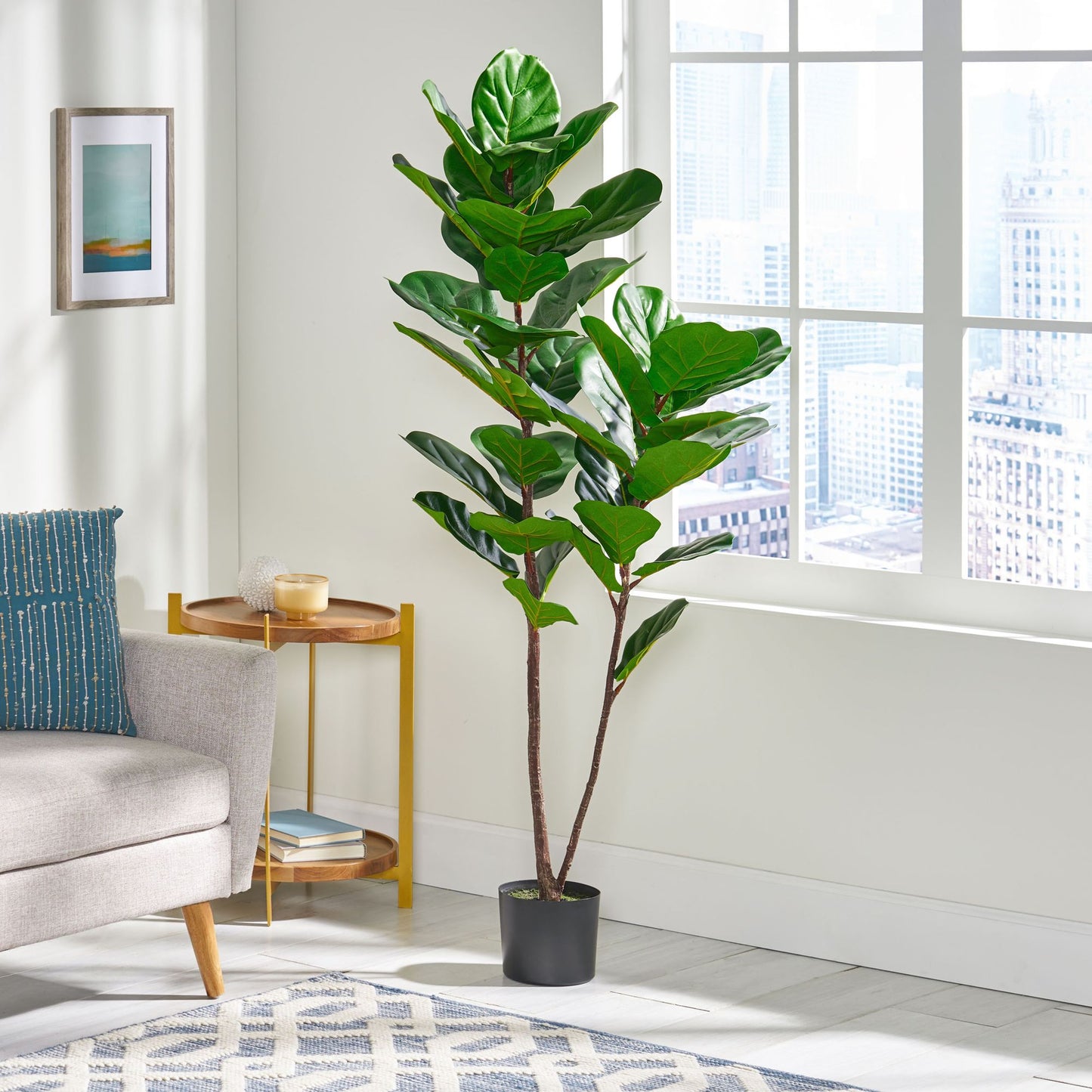 Artificial fiddle leaf fig tree with lush green leaves in black pot beside sofa in bright living room