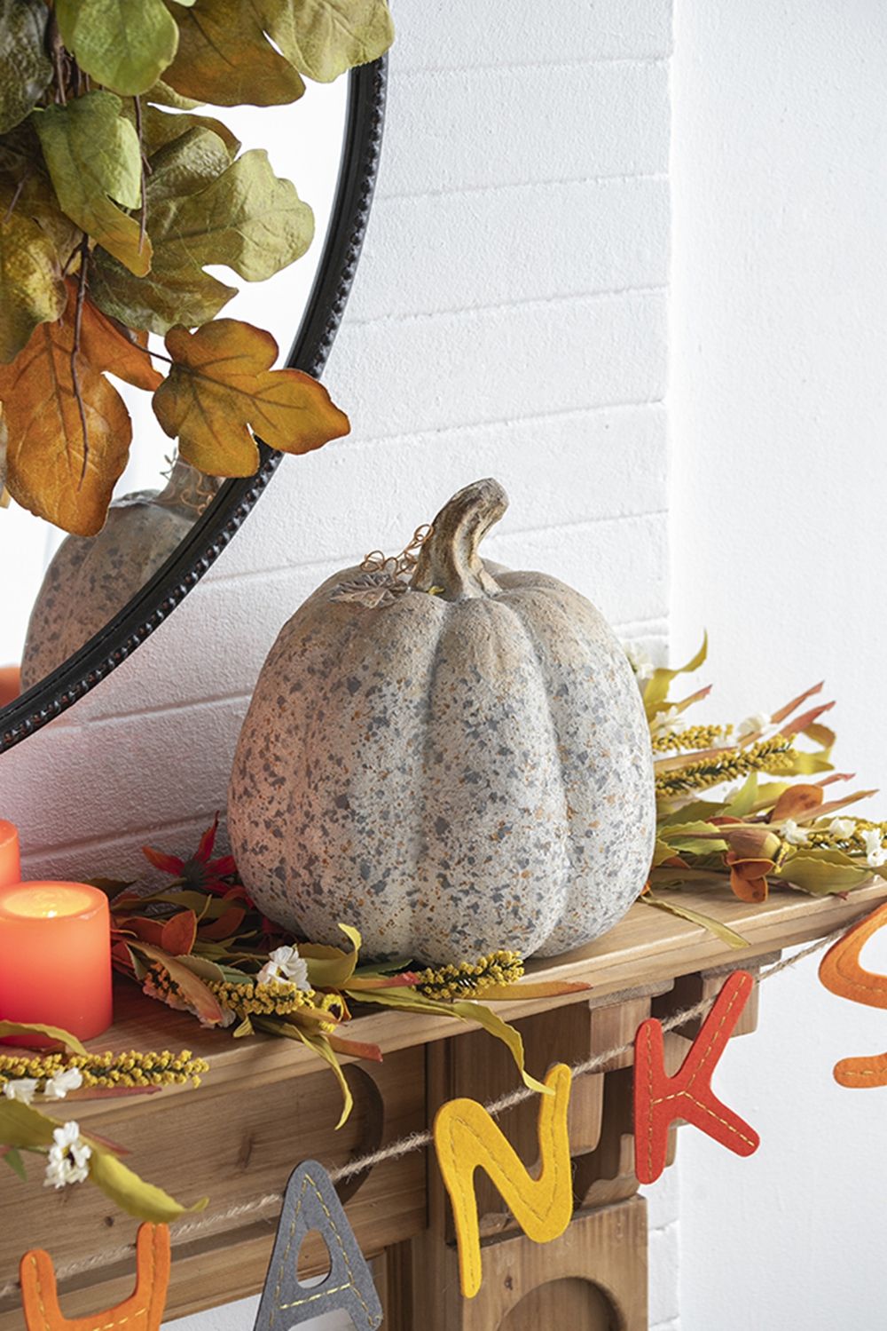 Decorative autumn mantel arrangement featuring a pumpkin and artificial flower picks set