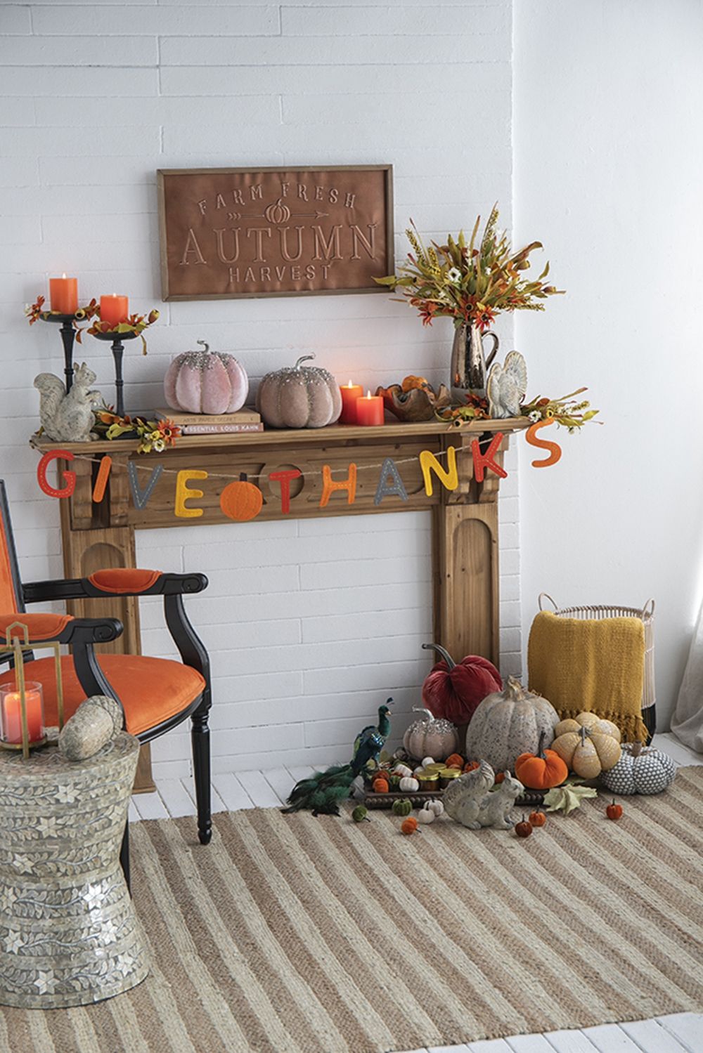 Decorative autumn mantel display featuring an artificial flower picks set among pumpkins and candles
