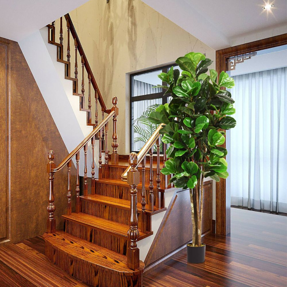 Lifelike artificial green plants indoor in a stylish pot next to a wooden staircase
