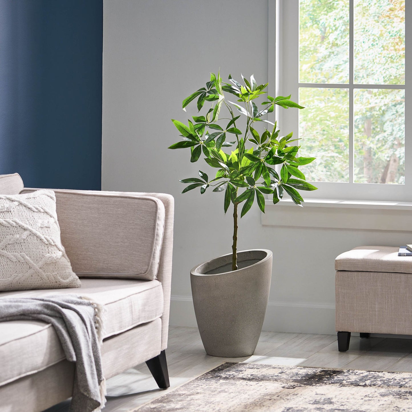 Artificial money tree plant in a gray pot displayed in a modern living room with natural light