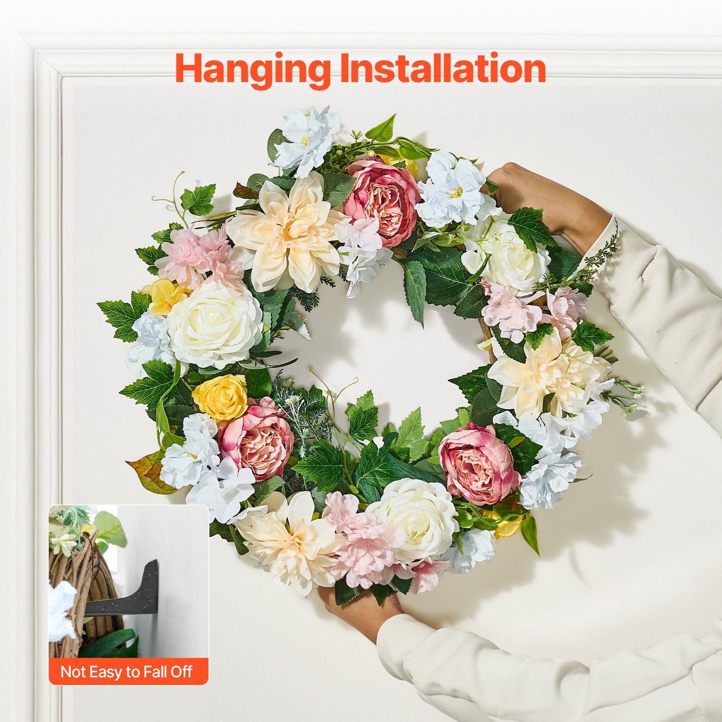 Hands hanging artificial peony hydrangea wreath with mixed flowers and green leaves on white wall