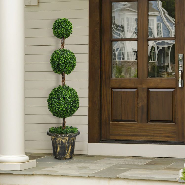Elegant artificial topiary tree in a decorative pot beside a wooden front door