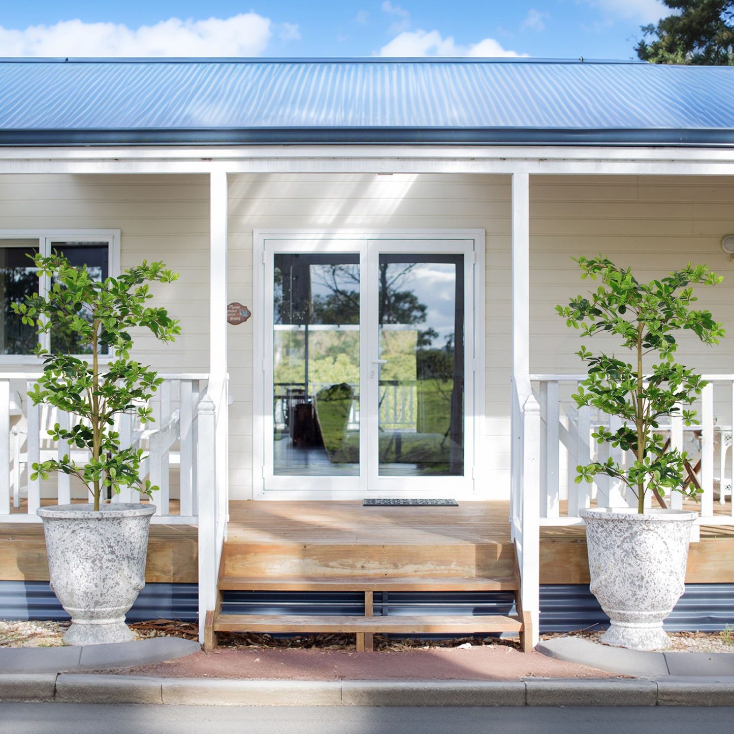 Two decorative artificial tung tree plants in stylish pots on a porch for home decor