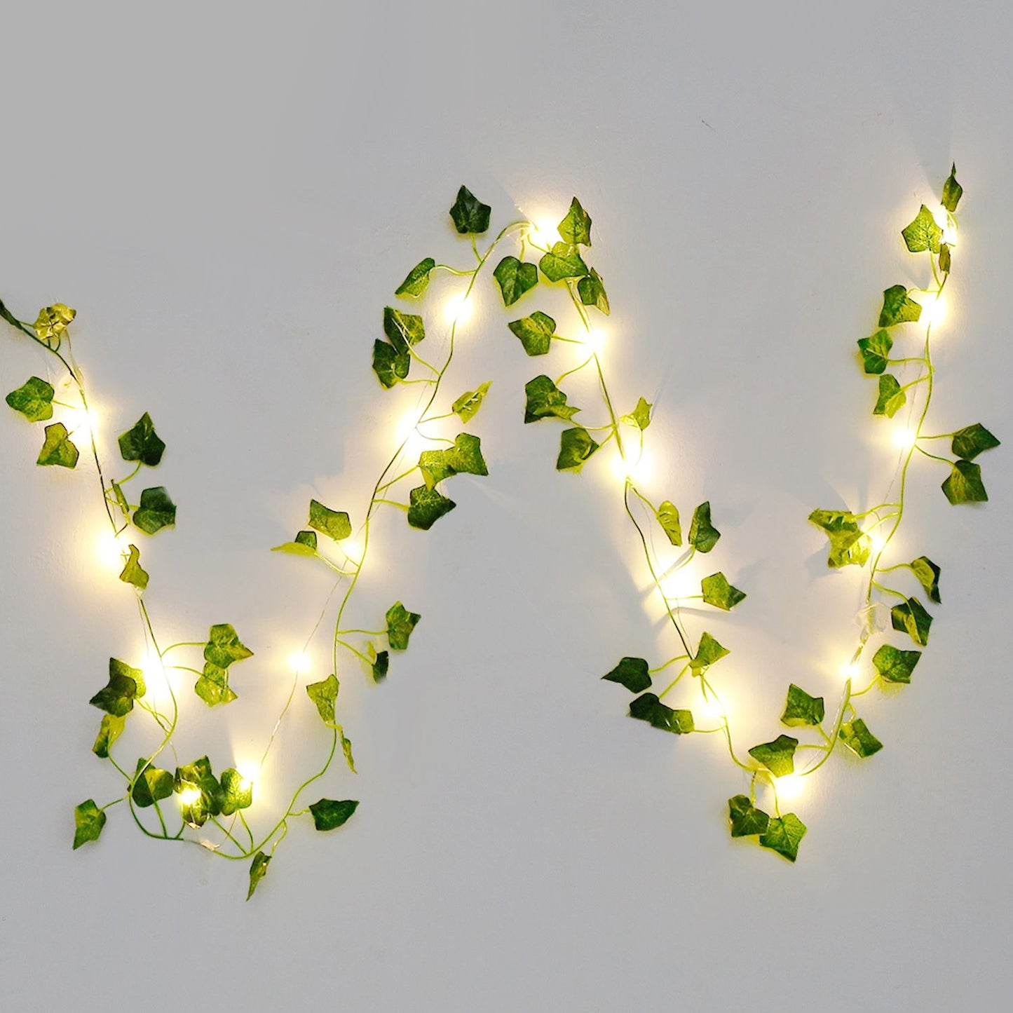 Warm glowing artificial ivy string lights with green leaves on a white background by FauxMart.com
