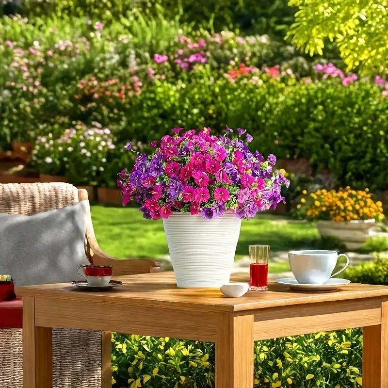Bright artificial flowers for home in white pot on wooden table in vibrant garden setting