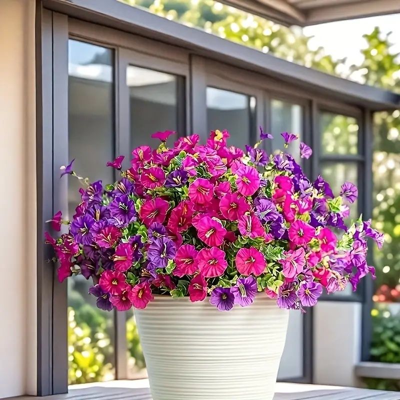 Bright artificial flowers for home in vibrant pink and purple hues arranged in a white decorative pot