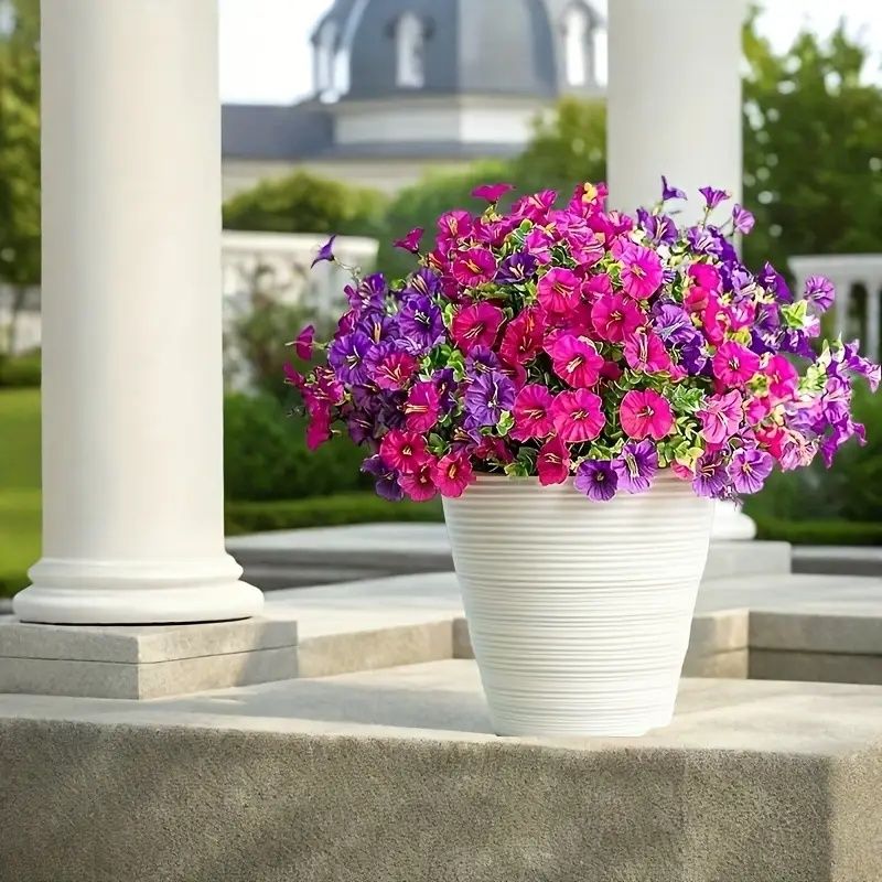 Bright artificial flowers for home in pink and purple colors displayed in a white pot outdoors