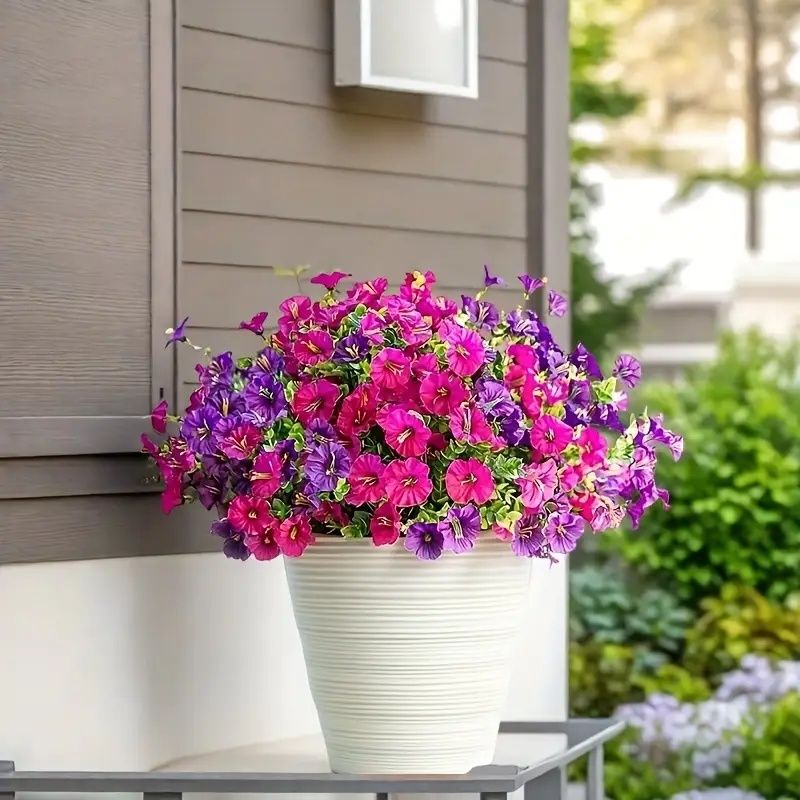 Bright artificial flowers for home in pink and purple arranged in a white decorative pot outdoors