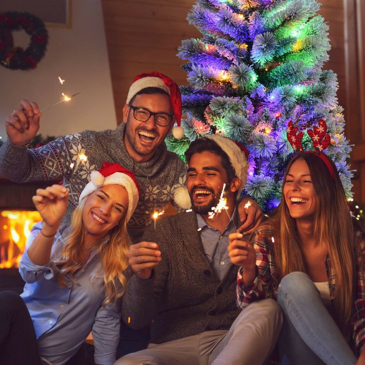 Happy group celebrating near a Christmas tree with 9 lighting modes holding sparklers indoors