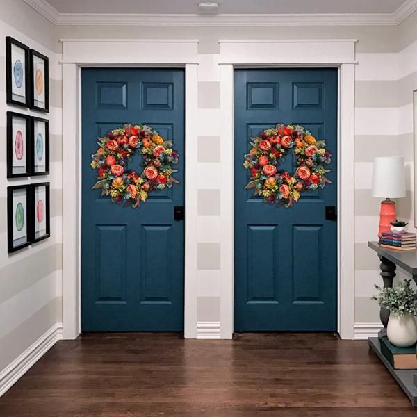 Artificial flower door wreath hanging on two blue interior doors with colorful floral arrangement