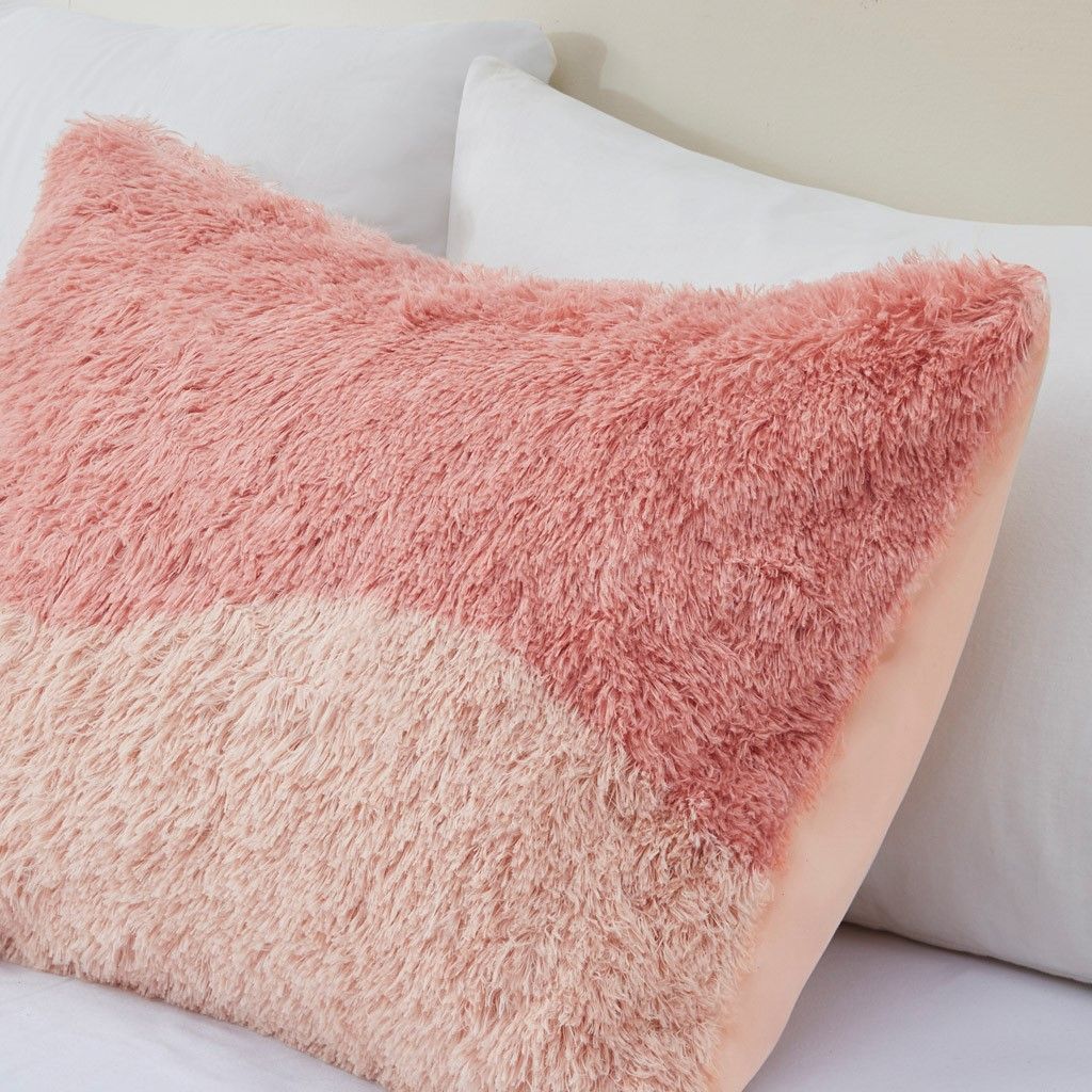 Close-up of ombre faux fur comforter set pillow in pink shades on white bed linens