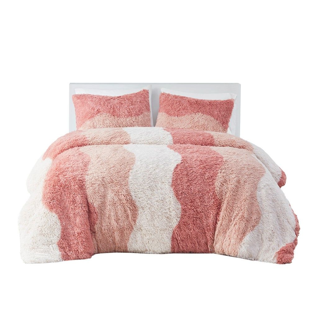 Ombre faux fur comforter set in pink and white wavy stripes with matching pillow shams on bed