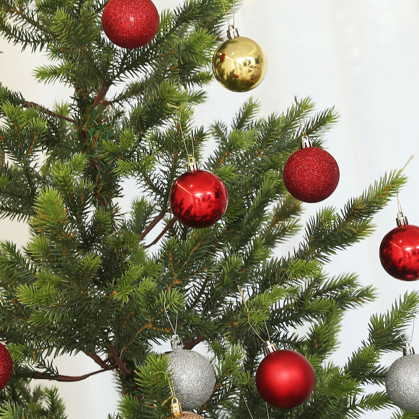 Close-up of a sparse artificial Christmas tree decorated with red and gold ornaments