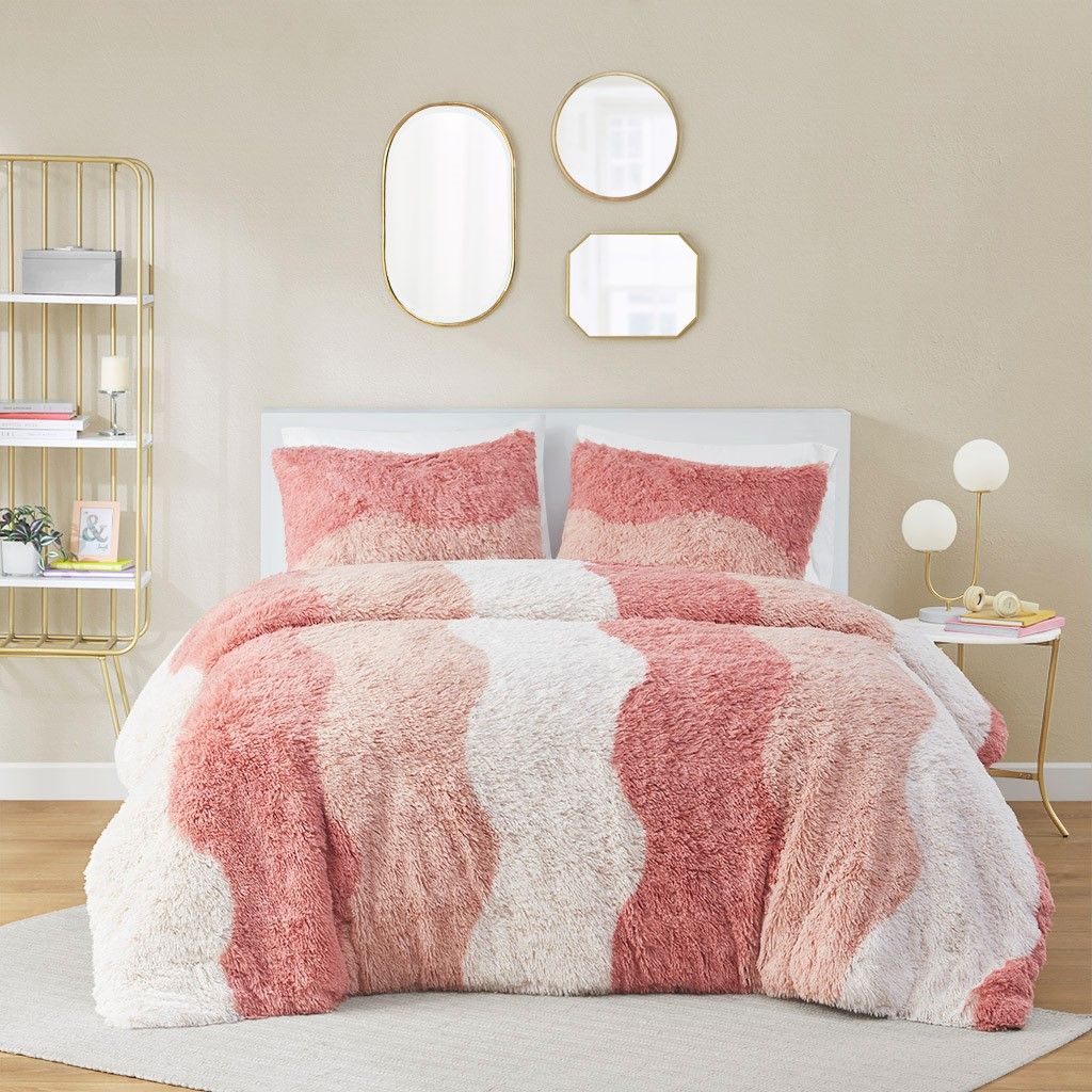Ombre faux fur comforter set in shades of pink and white with matching pillow shams on bed