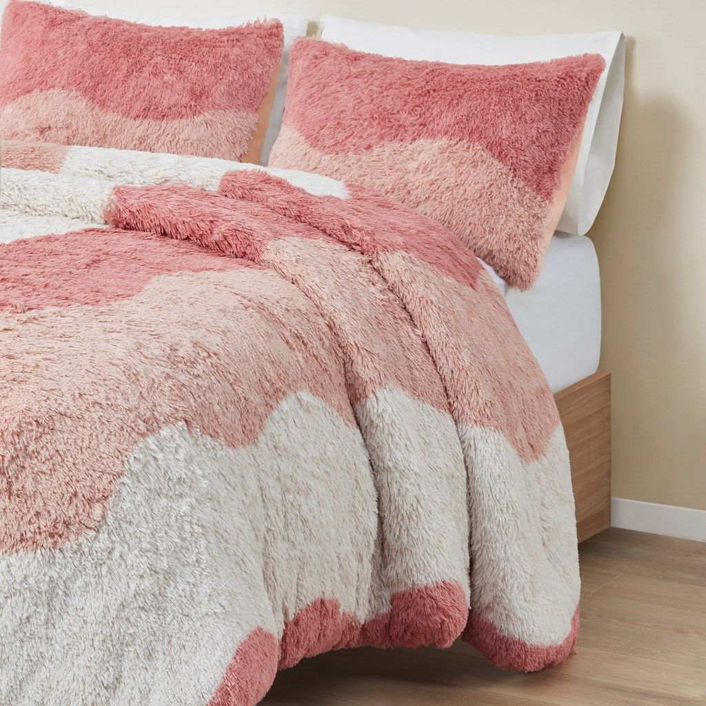 Ombre faux fur comforter set in shades of pink and white on a neatly made bed