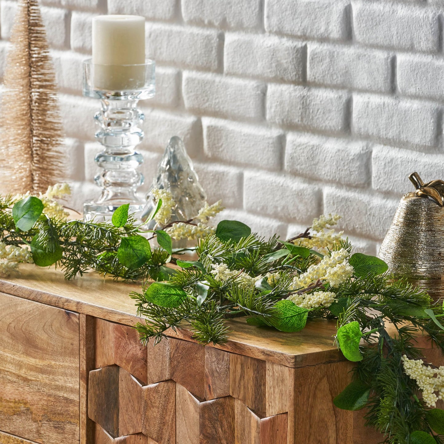 Eucalyptus Christmas garland with green leaves and white flowers displayed on wooden sideboard with holiday decor