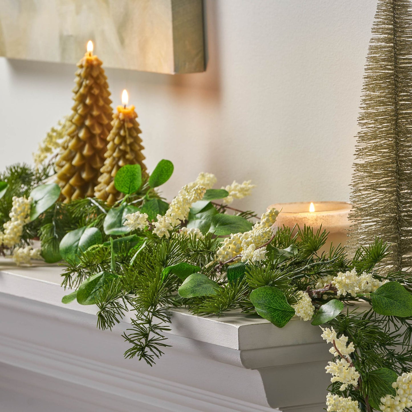 Eucalyptus Christmas garland with green leaves and white flowers decorated on a mantel with candles