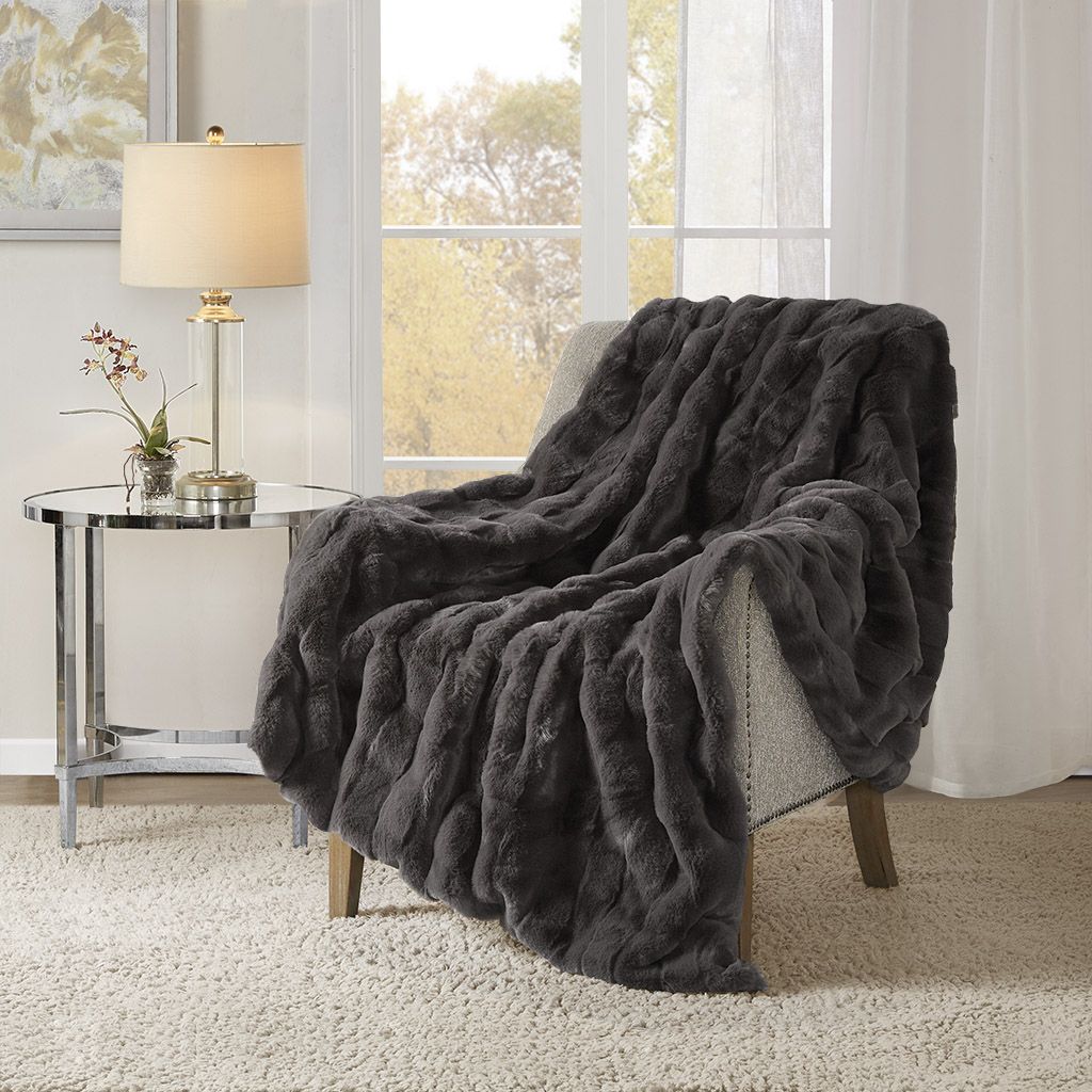 Dark gray faux fur throw blanket draped over a chair in cozy living room setting