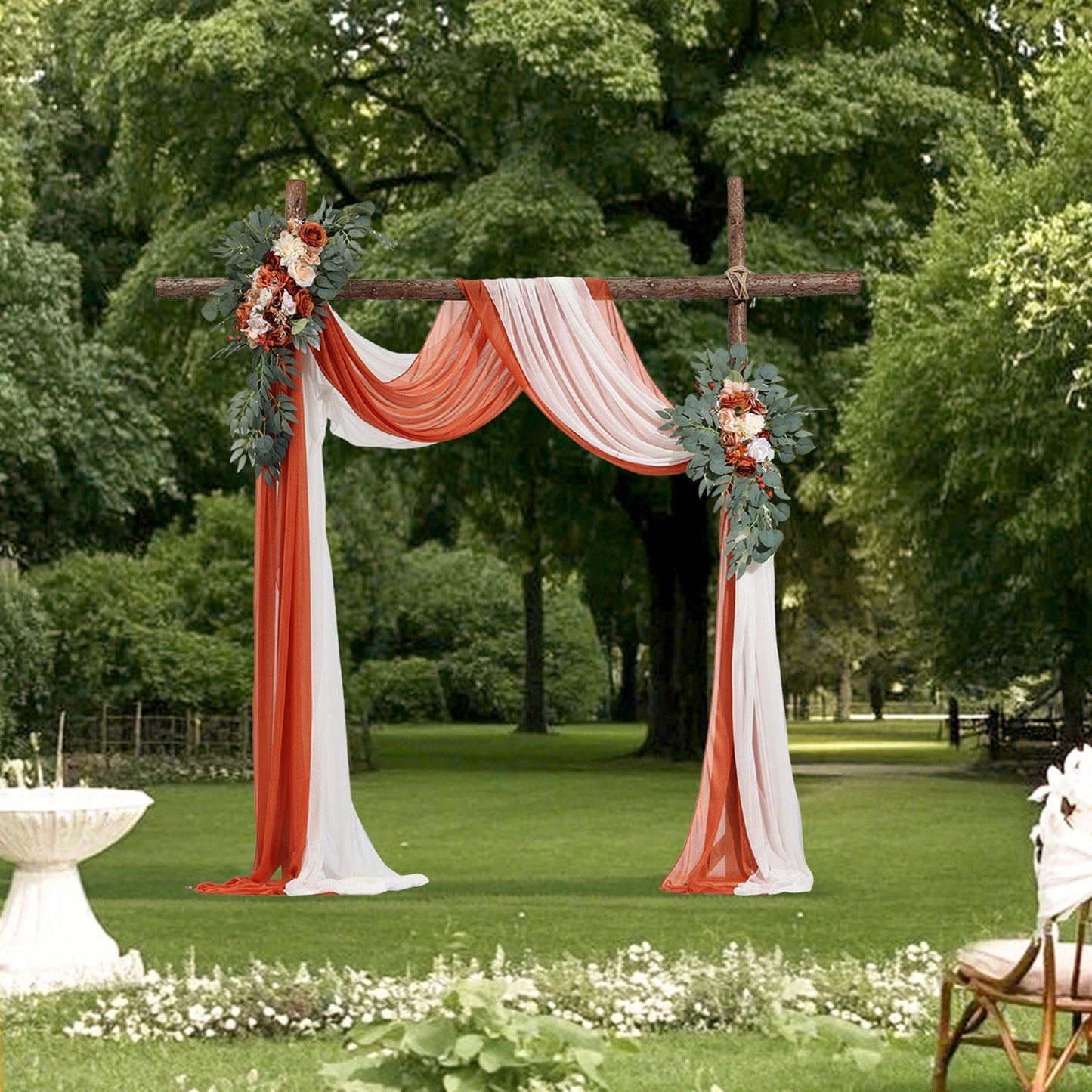 Outdoor wedding arch decorated with burnt orange wedding arch flowers and white draped fabric in a garden