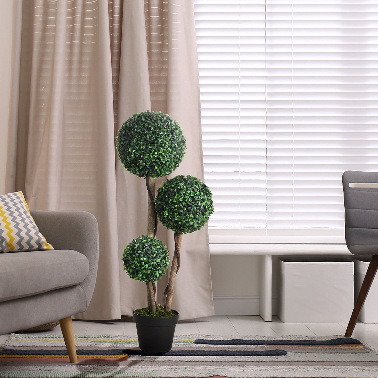 Artificial boxwood topiary tree with three green spheres in black pot placed in a modern living room