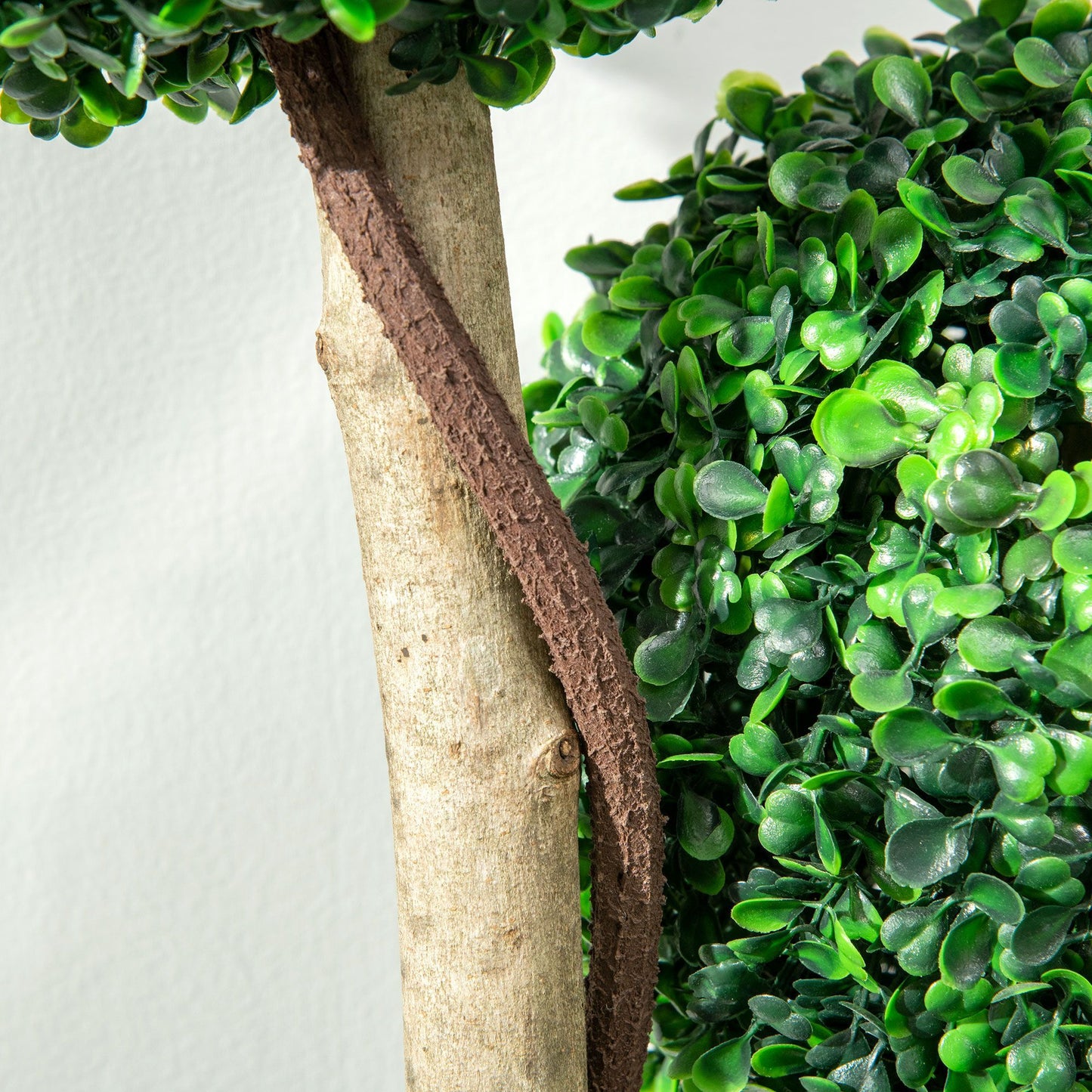 Close-up of artificial boxwood topiary tree with textured trunk and vibrant green leaves
