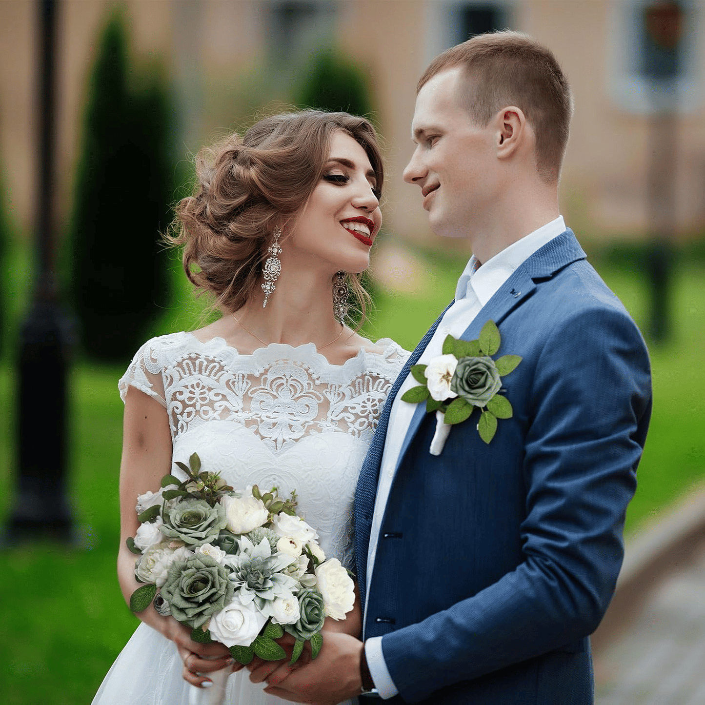 Bride and groom holding a purple artificial flower arrangement during outdoor wedding photoshoot