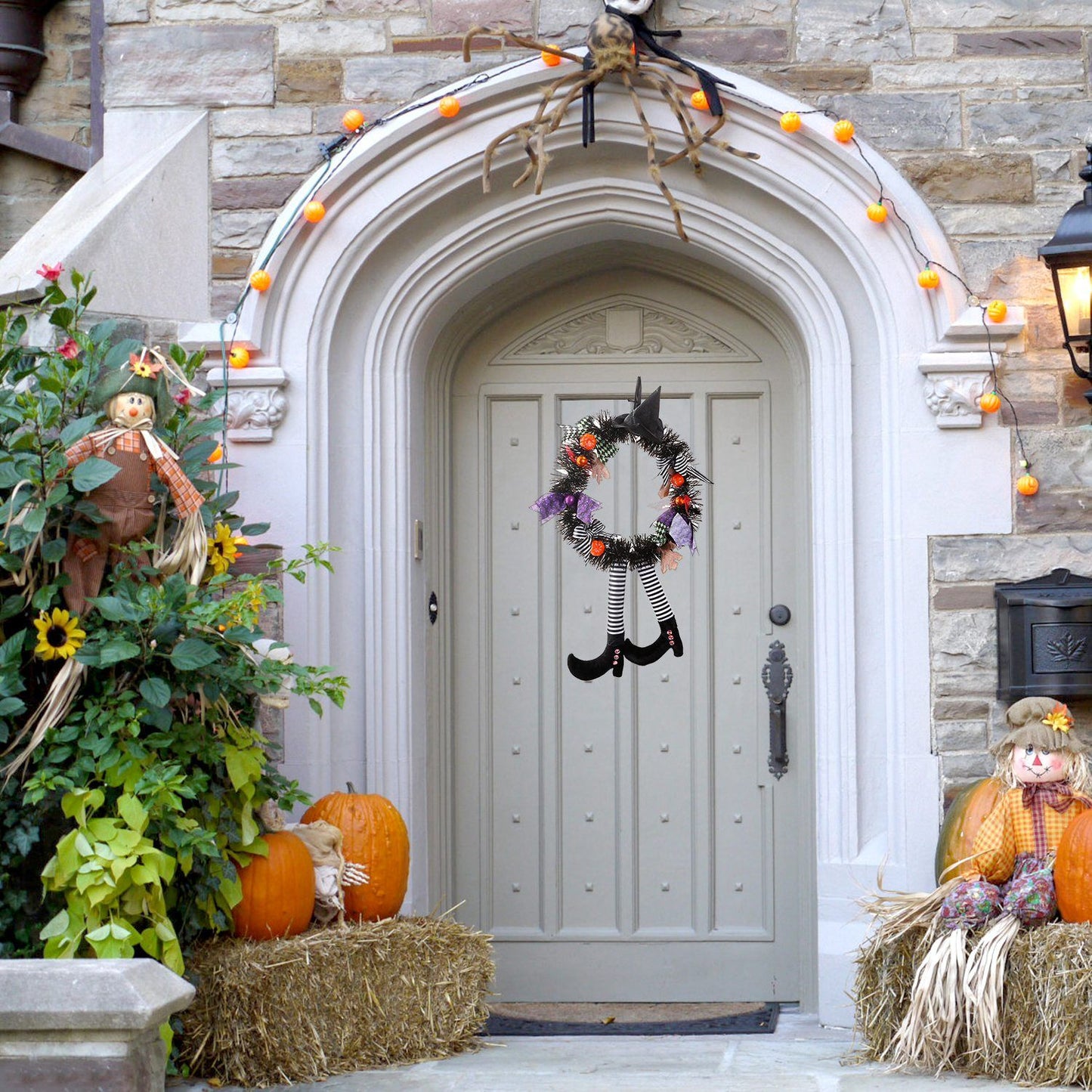 Halloween witch wreath with striped legs hanging on gray door surrounded by pumpkins and fall decorations