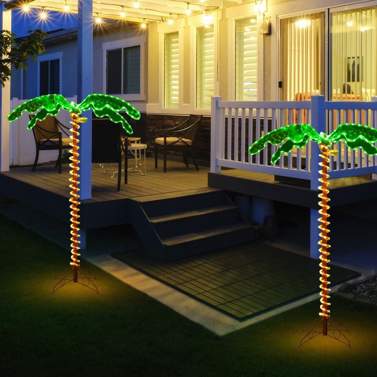 LED palm tree decor glowing green and yellow lights set in a backyard patio at night