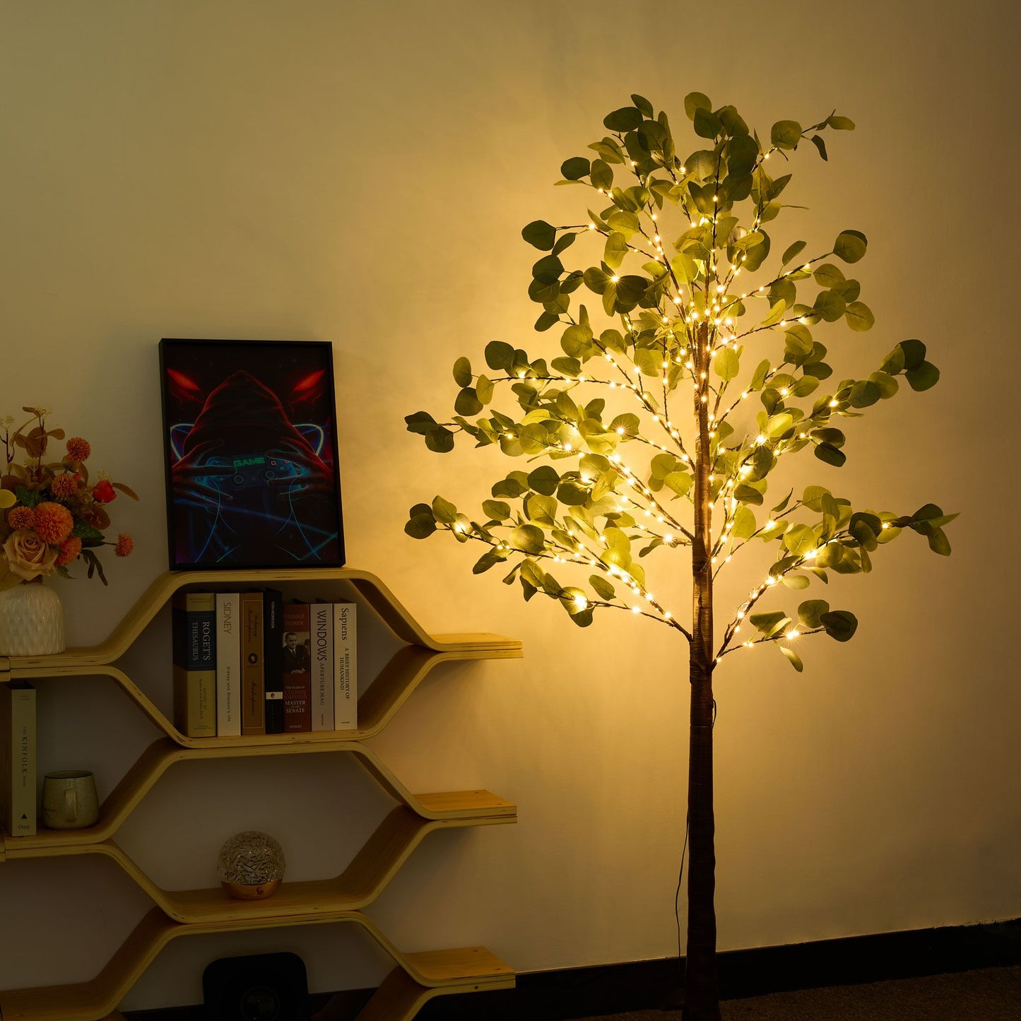 Lighted artificial olive tree with warm white fairy lights standing next to a wooden bookshelf