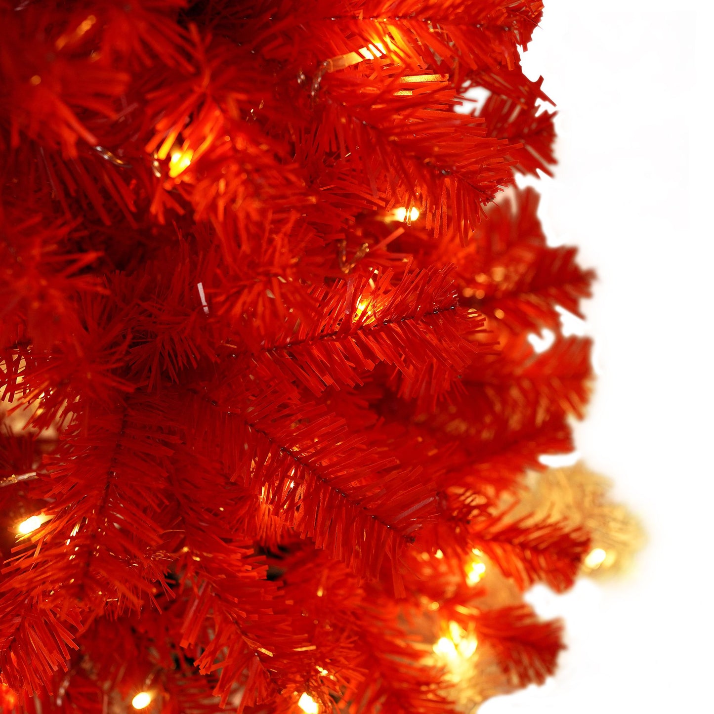 Close-up of bright orange artificial branches with glowing lights on lighted santa hat christmas tree