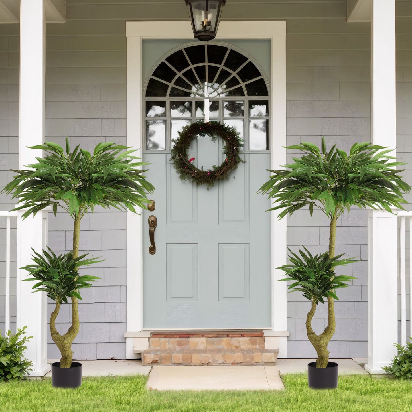 Two long artificial plants for indoors placed by a welcoming entrance with a decorative wreath