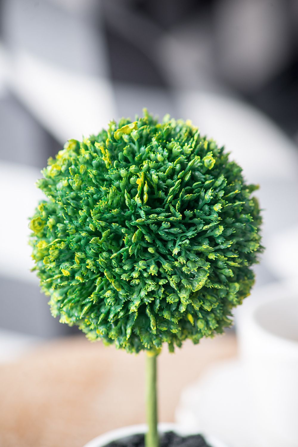 Close-up of a green artificial plant from a mini faux topiary set with round foliage on a stem
