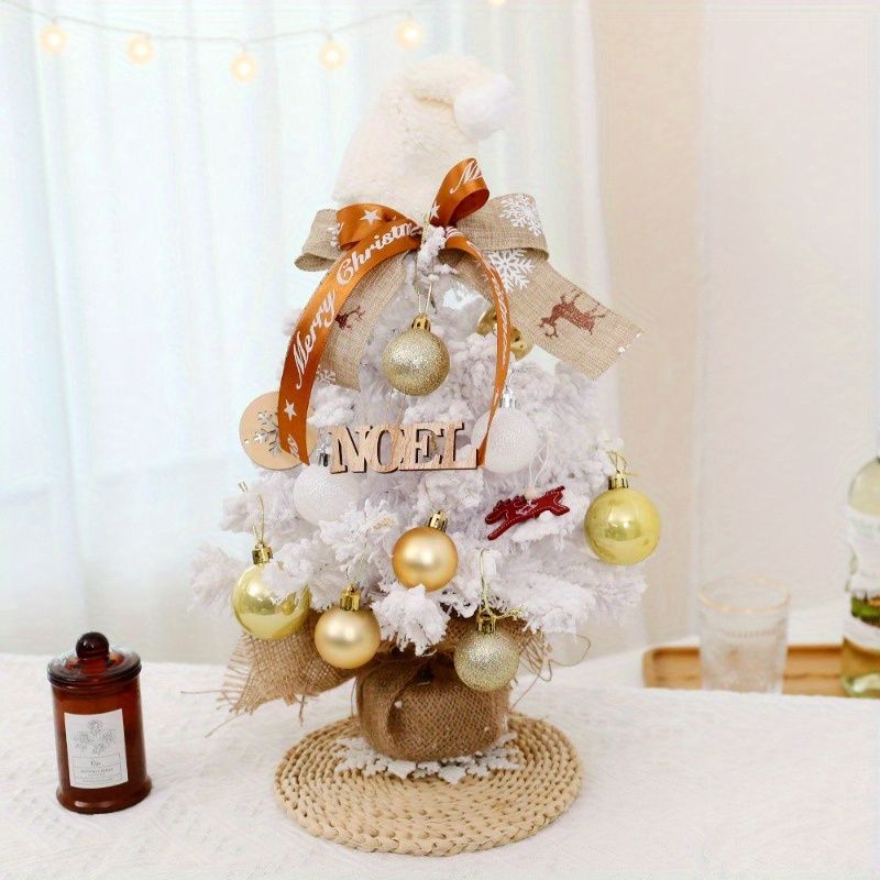 Decorative mini table top Christmas tree with gold ornaments, a festive ribbon, and a snowy appearance