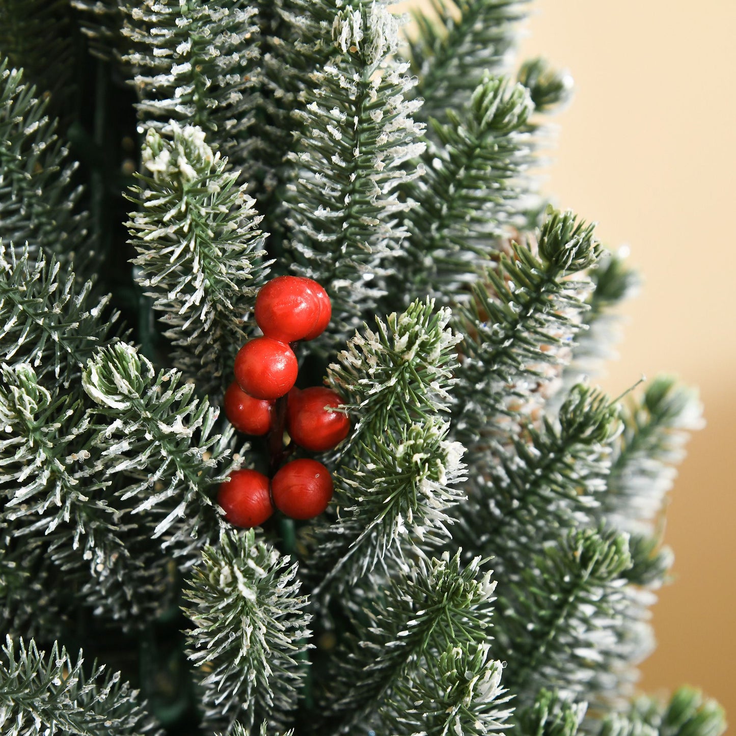 Miniature snow flocked Christmas tree with red berries for festive holiday decoration