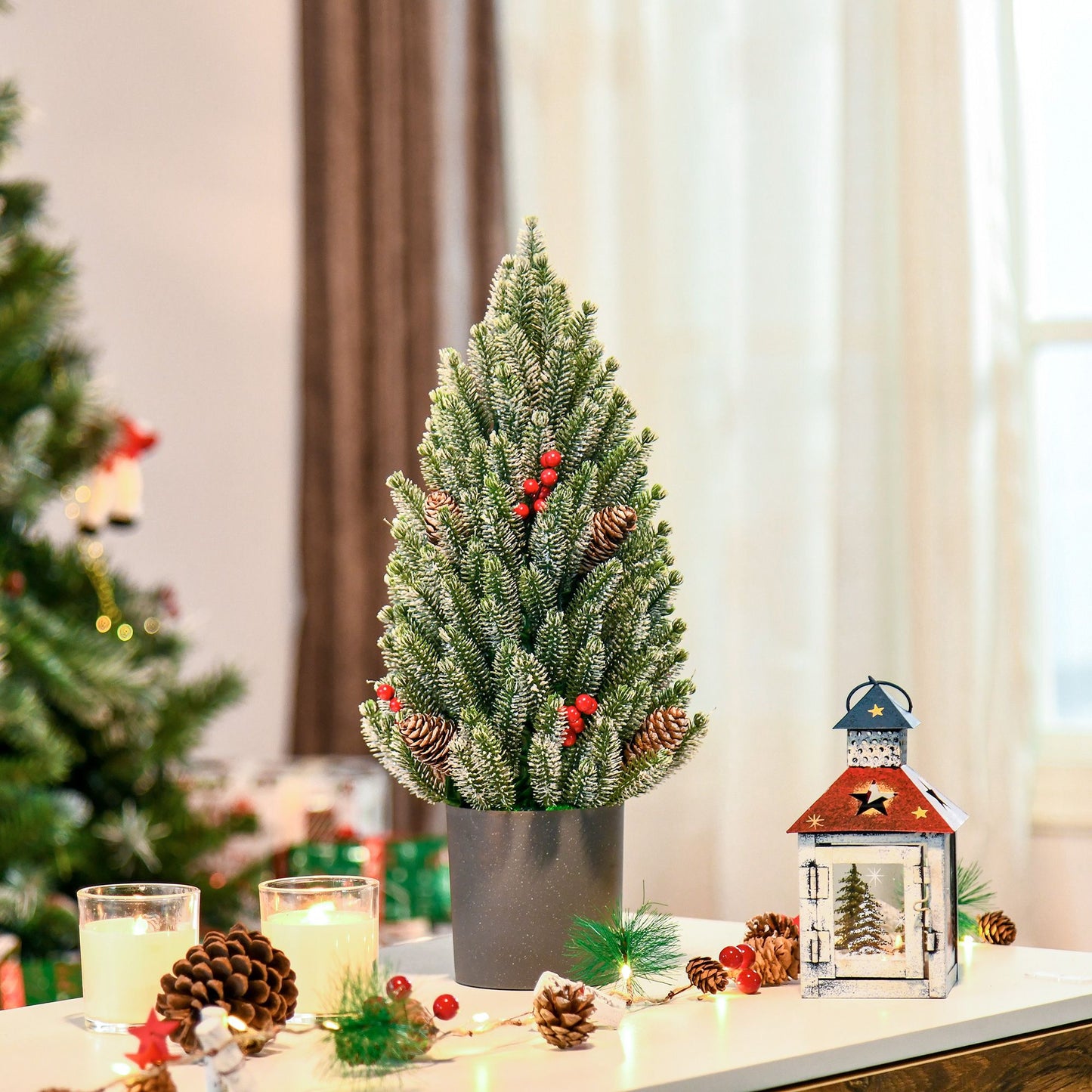Miniature snow flocked Christmas tree with red berries and pinecones in a decorative pot
