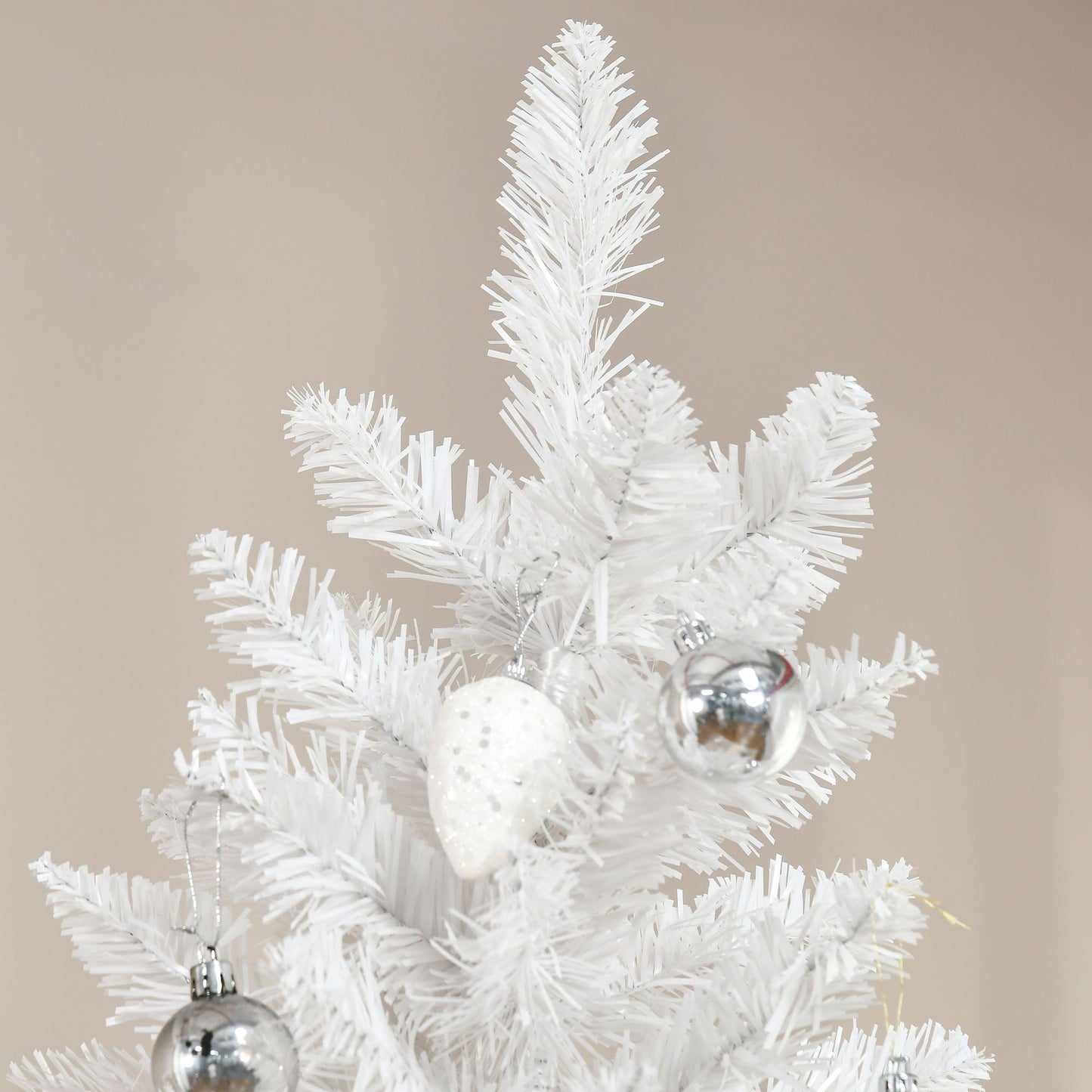 Close-up of white artificial Christmas tree with silver and white ornaments on pink and white artificial Christmas tree