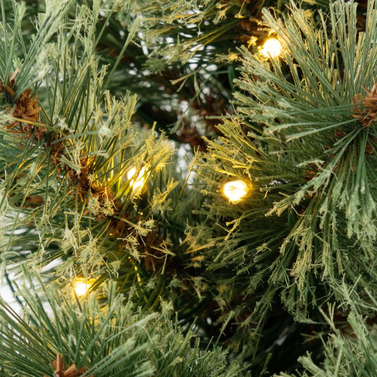 Close-up of pre-lit artificial Christmas tree with warm white lights for festive decoration