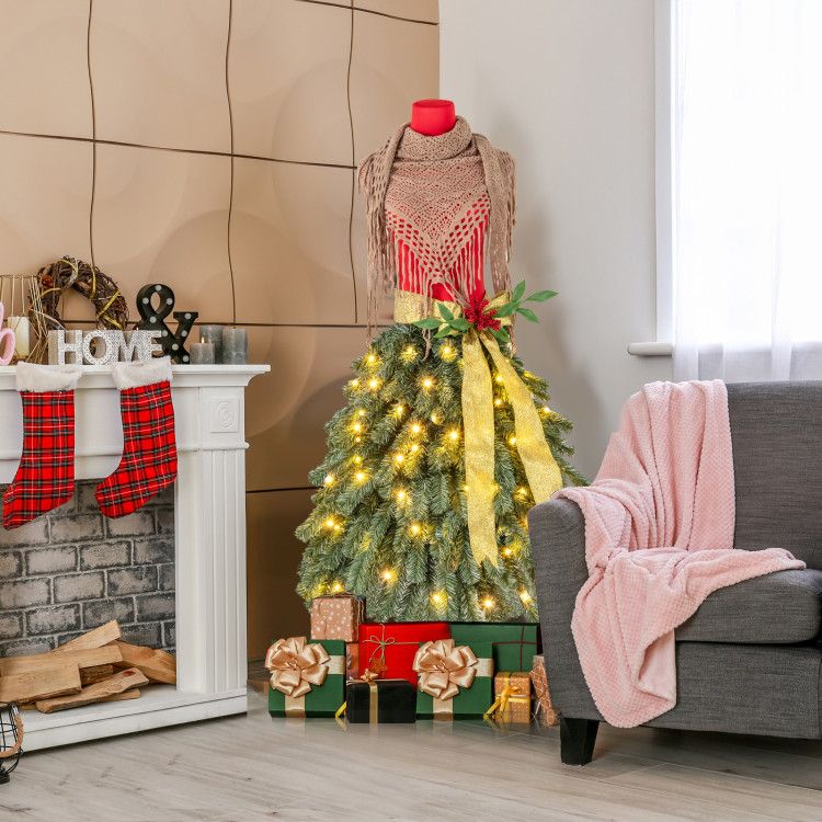 Pre-lit mannequin Christmas tree decorated with lights and gifts in a cozy living room setting