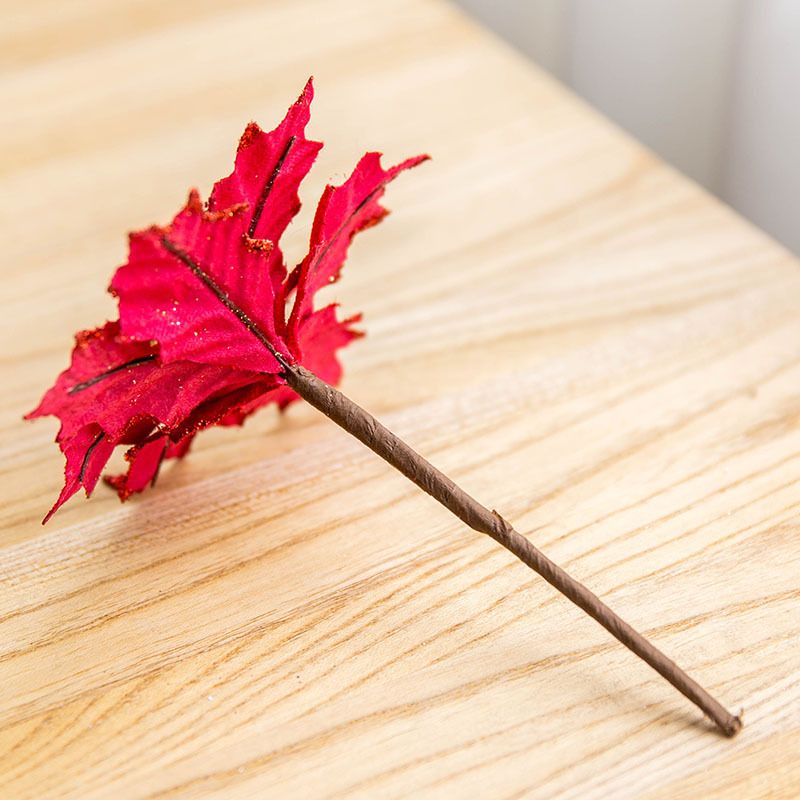Red rattan horn Christmas tree ornament with gold glitter detail on wooden surface