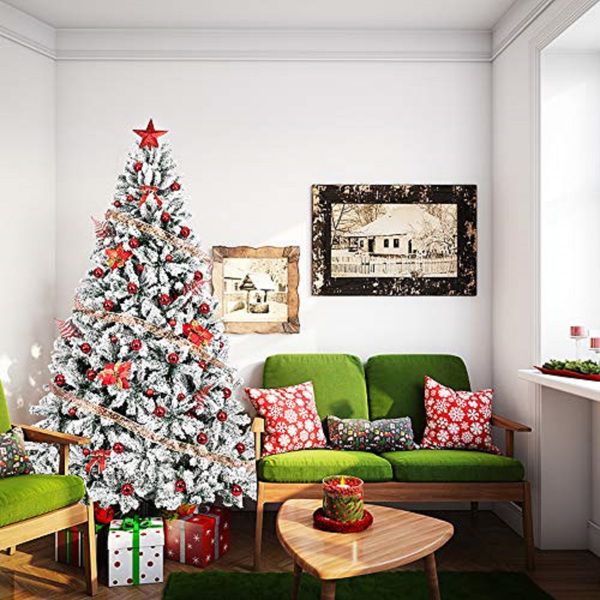 Snow flocked artificial Christmas tree adorned with red ornaments in a cozy living room setting