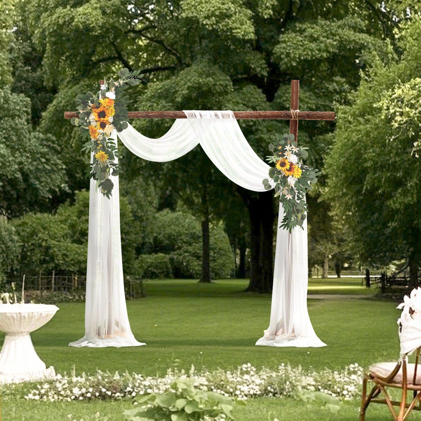 Sunflower wedding arch decor with white drapes and greenery set up outdoors on grass